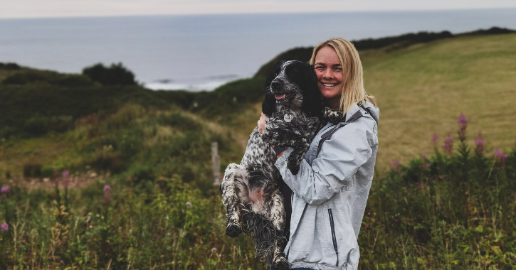 woman stood smiling at camera holding a springer spaniel dog on the Durham Heritage Coast.